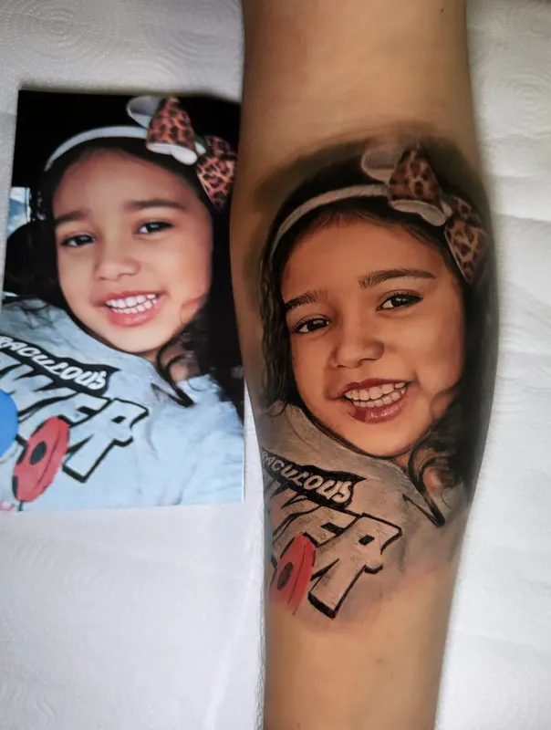 Retrato infantil em realismo tatuado no braço