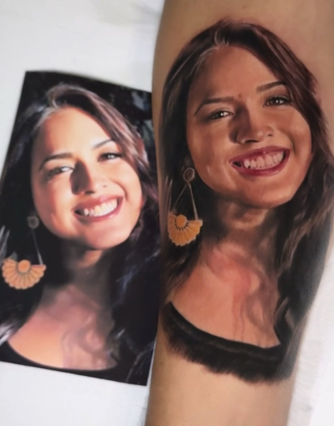 Retrato de mulher tatuado no braco ao lado da foto de referencia
