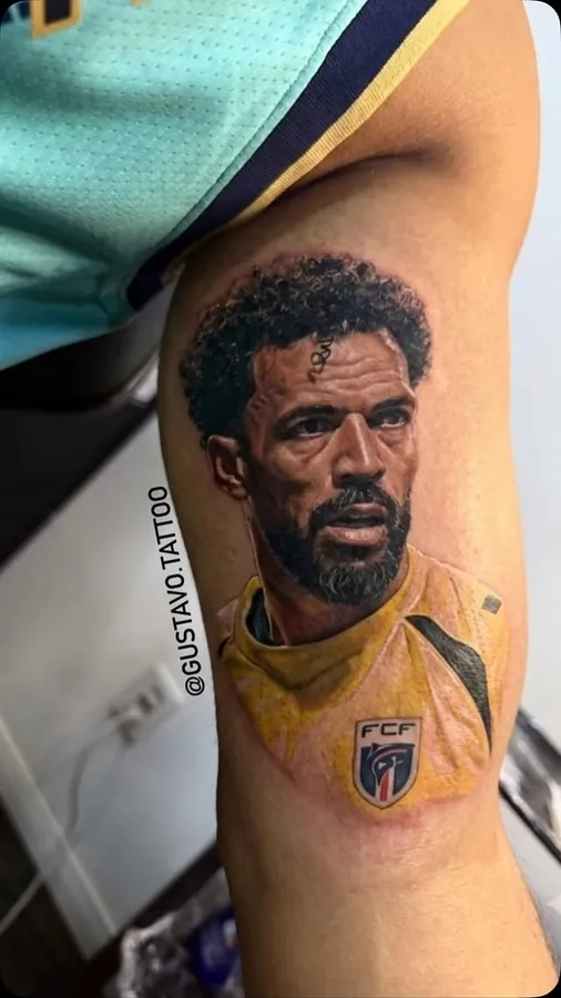 Retrato de jogador de futebol tatuado na perna, em cor
